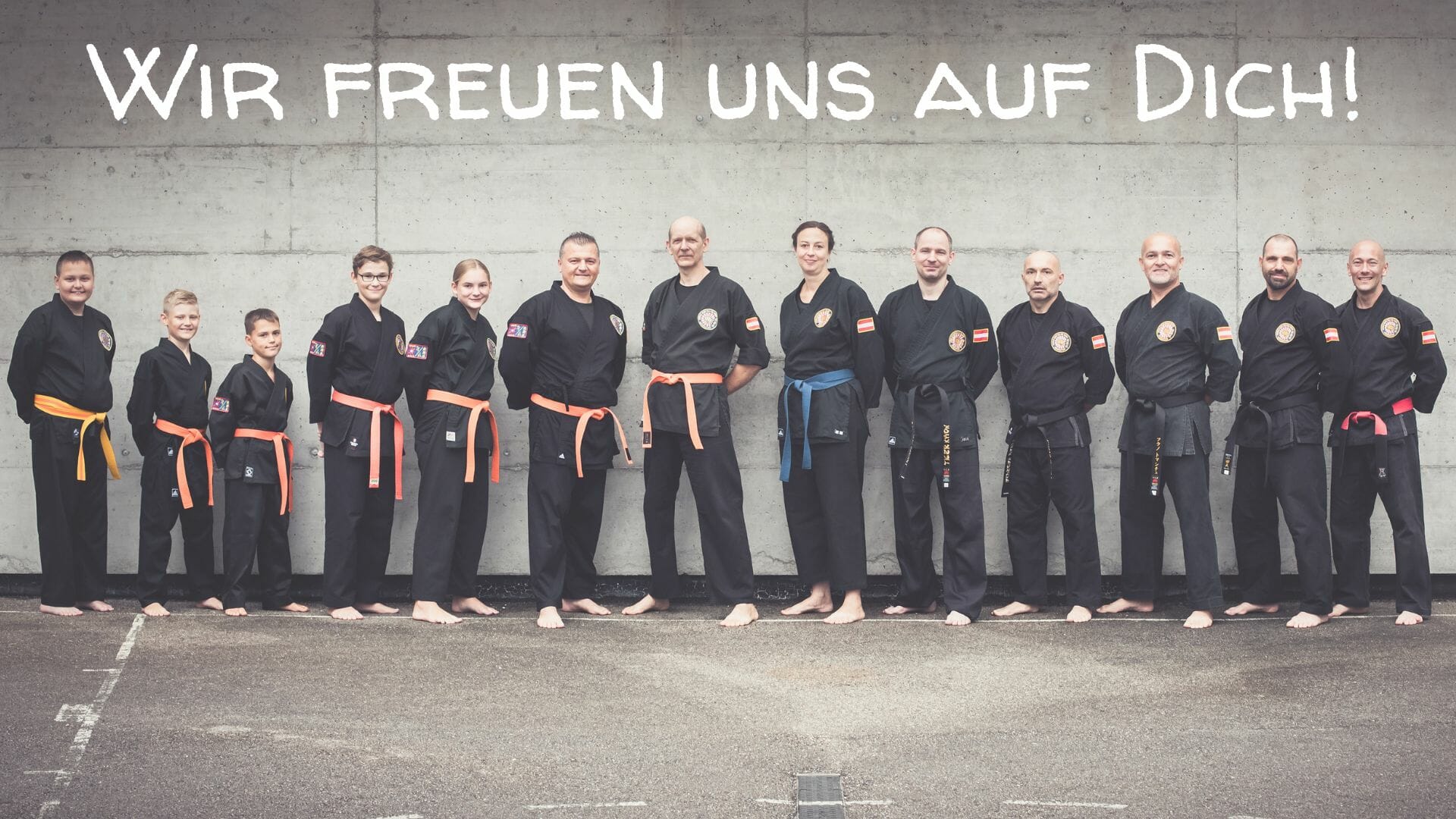 Kampfkünstler im schwarzen Karateanzug welche für ein freundliches Gruppenfoto im Freien posieren.
