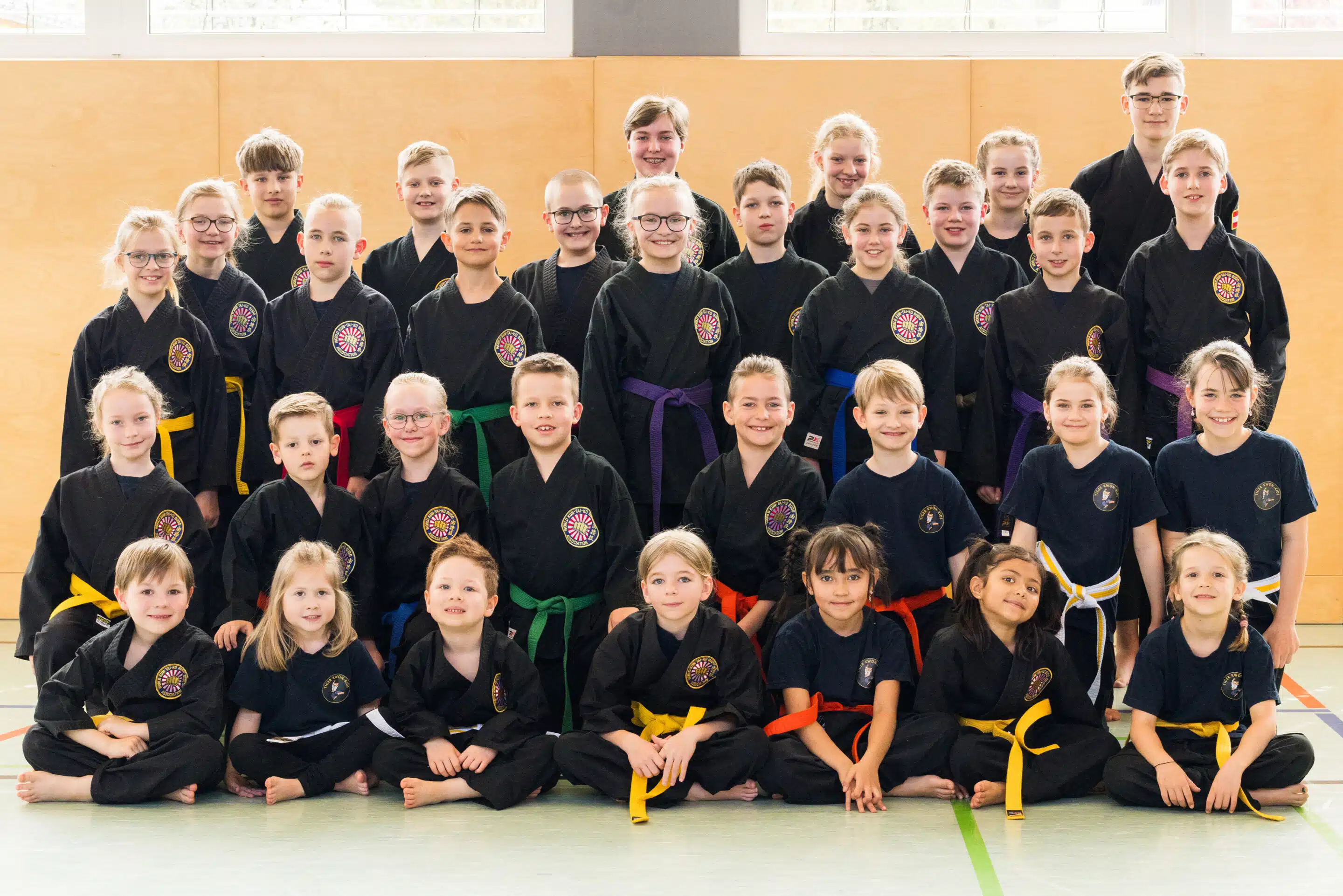 Gruppenfoto von Kindern im Karateanzug in einer Turnhalle.